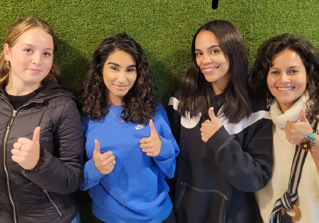 Na de theoriecursus Hoofddorp steken vier jonge vrouwen hun duim op voor een grasmuur